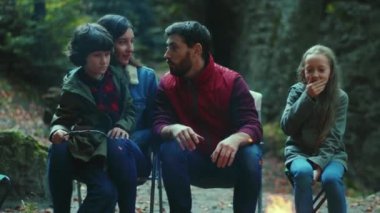 Orman ailesinde sonbahar akşamı kamp ateşinin yanında oturur ve korkunç hikayeler anlatırlar. Ebeveynleriyle birlikte çocuklar ormanda dinleniyorlar. Çocukluk ilişkisi kamp kuruyor. Kapatın. Yavaş çekim