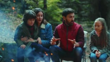 Sonbaharda aile kamp ateşinin yanında oturur ve korkunç hikayeler anlatır. Ebeveynleriyle birlikte çocuklar ormanda dinleniyorlar. Çocukluk ilişkisi kamp kuruyor. Kapatın. Yavaş çekim