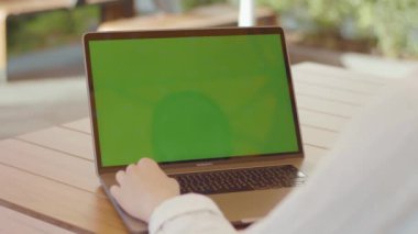 NEW YORK - 5 Eylül 2020: Kadın elinin yakın çekim görüntüleri klavyede beyaz bluz yazıları giyer, yeşil ekranlı yeni model dizüstü bilgisayarda dokunmatik ekran kullanır. Taşınabilir bilgisayarı olan genç bir işçi