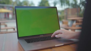 NEW YORK - 5 Eylül 2020: klavyede kadın eli görüntüleri. Bilgisayarda çalışan siyah elbiseli, tanınmayan genç bir kadının yakın plan çekimi. Yeşil ekranlı dizüstü bilgisayar kullanan programcı