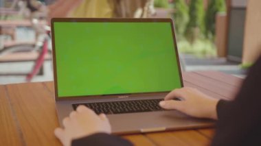 NEW YORK - 5 Eylül 2020: Yöneticinin yakın plan görüntüsü dizüstü bilgisayarın klavyesinde yazan siyah kıyafetler giyiyor. Yeşil ekranlı taşınabilir bilgisayar kullanan genç bir kadının sırt çekimi, sohbet, sörf