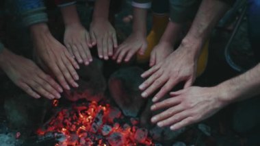 Hafta sonu ormanda şenlik ateşinde ısınan genç aile ellerini kapatıyoruz. Çocuk kampı turist hafta sonu pikniği. Karanlıkta. Yavaş çekim