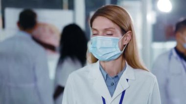 Aşırı yüklü bir hastanede sosyal mesafesini korumak için solunum maskesi takan orta yaşlı profesyonel kadın doktor portresi. Karantina.
