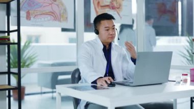 Asyalı profesyonel erkek doktor sosyal mesafeler için dizüstü bilgisayarlı video kaset vasıtasıyla müşterilere danışmanlık yapıyor. Sağlık hizmetleri. Hastaneler. Uzak iletişim.