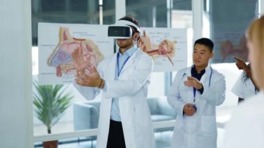VR kulaklıklı genç beyaz adam ofis içi çalışma alanı hastanesini alkışlayan sağlık çalışanlarına etkileyici proje sunumu yapıyor. Teknolojiler. Gelecek..