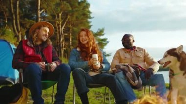 Doğada kamp ateşinin yanında oturan komik arkadaşlar. Gençler oyunlar hakkında konuşurlar, köpeklerin gülümsemesiyle mutlu olurlar. Tatil turizmi macerası. Yavaş çekim