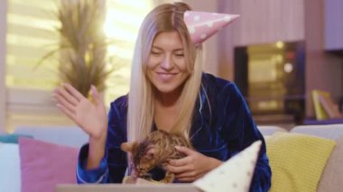 Neşeli, güzel, sarışın bir kadın. Ailesiyle internetten sohbet ediyor. Doğum gününü kutluyor, Bengal kedisiyle evde pijama partisi yapıyor..