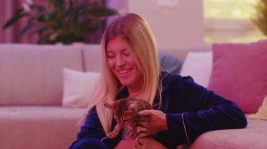 Genç, çekici, neşeli bir kadın. Bengal kedisini kucağında tutuyor. Sevimli tekir kedisi..