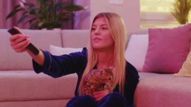 Çekici, komik, sevimli kadın Bengal kedisini tutuyor birlikte komik filmler izliyorlar favori TV kanalının tadını çıkarıyorlar evde eğleniyorlar..