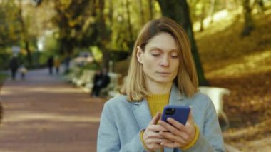 Yüzü hasta genç bir kadın güneş ışığında parkta yürürken baş ağrısı çekerken soğuk öksürük hisseder. Sarışın, stresli bayan. Portre ağrısı yorucu. Kapatın. Yavaş çekim