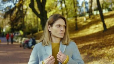 Baş ağrısı çeken genç bir kadının portresi soğuk hapşırıklar hissediyor sonbahar parkında gün ışığında duruyor. Sarışın, stresli bayan. Ağrı yorgun. Hastasın. Kapatın. Yavaş çekim