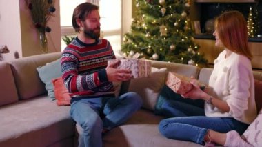 Kafkasyalı mutlu bir çift, boks gününde süslenmiş ağacın yanında Noel 'i kutluyorlar. Ev xmas atmosferi.