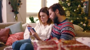 Kafkasyalı genç bir çift evde kalıp online mağaza akıllı telefon uygulaması e-ticaret alışverişinde hediye seçiyor..