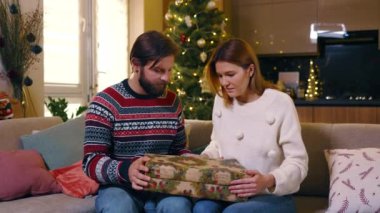 Mutlu evli çift hediye kutusunu açıyor ve Noel için harika bir kedi yavrusu alıyor. Güzel kediler. Genç bir aile. Noel tatili. Aile kavramı.