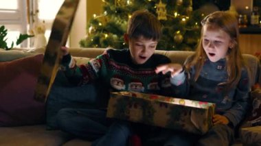 İki kardeşin hediyelerini açıp içinde sihirli ışıklar parlayan büyük bir Noel kutusunu açması inanılmaz bir şey. Kış tatili Atmosfer. Çocukluk.