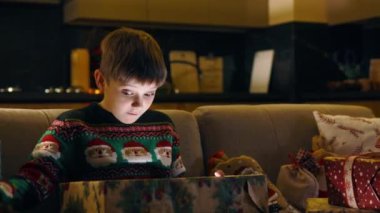 Şaşkın şirin çocuk büyük Noel hediyesini açıyor ve sihirli ışıkların içine parlak bir şekilde bakıyor. Noel hediyesi. Kış tatili Çocuklar işte. Duygular konsepti.