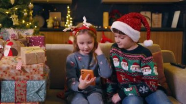 Noel şapkası takan komik çocuklar akıllı telefondan arıyor evde birlikte oynayan arkadaşlarıyla bağlantı kuruyor. Kış tatili Aile.
