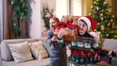 Komik şapkalar takan ve evde hediyelerle oynayan güzel çocuklardan oluşan mutlu bir takım. Noel tatili. Çocukluk ve aileler.