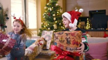 Evde Noel hediyeleriyle oynayan şapkalı iki sevimli çocuğa hayranım. Kış kutlaması. Tatil konsepti. Aileler.