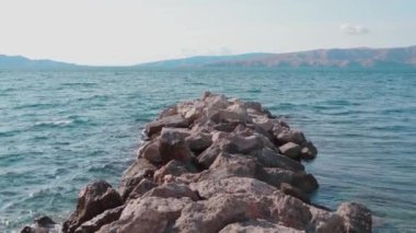 Büyük kayalarla panoramik deniz manzarası. Yatay görüntü. Doğa manzarası. Taşlara ve turkuazlara yakın temiz su. Deniz kenarında. Rahatla, Hırvatistan 'a gidiyoruz. Arka planda dağlar. Gündüz