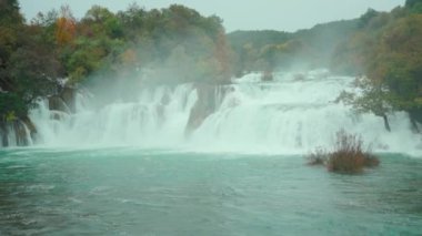 Ormanın derinliklerinde bulutlu bir gün ve inanılmaz bir şelale. İnanılmaz şelalenin yatay görüntüsü. Sonbaharda renkli ağaç yaprakları. Hırvatistan 'daki ulusal park, açık hava, sansür, koruma, gezinti