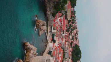 Doğal güzel manzaranın dikey drone görüntüleri. Turkuaz sakin deniz manzarası ve kırmızı çatılı evler. Dağ manzarası, dağlık arazi. Gökyüzü açık. Hırvatistan. Renkli, yaşam tarzı, açık hava, rahatla