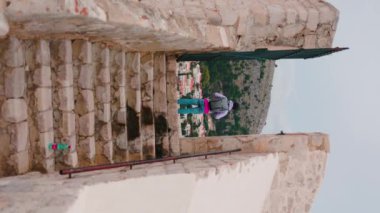 Renkli spor elbiseli turistin arka planı. Dağlara bakan bir adam. Dikey görüntü. Merdivenleri olan tarihi bir yer. Açık havada. Seyahat ediyorum. Kavram, fikir, tatil, antik, gezi, gelenek