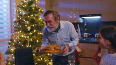 Mutlu yaşlı büyükbaba sıcak hindiyi aile üyeleriyle iletişim masasına koyuyor. Güzel Kafkas ailesi Noel 'i geçiriyor.