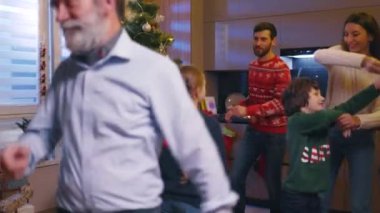 Beyaz, mutlu, beş kişilik bir aile Noel ağacı etrafında dans edip Noel şarkıları söylüyor ve evde eğleniyorlar. Buluşma. Kış gelenekleri.