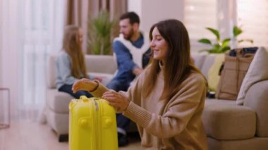 Genç ve güzel bir bayan kameraya bakıp gülümsüyor. Giysilerini seyahat çantasına koyuyor. Arka planda baba ve kızının konuşmaları var. Mutlu ol. Turizm çifti macera yaşam tarzı. Yavaş çekim