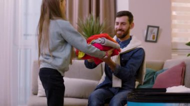 Baba-kız gülüşü yakın çekim odasında kanepede oturan giysileri seyahat çantasına koyar. Sarılmak. Mutlu ol. Turizm çifti macera yaşam tarzı. Yavaş çekim