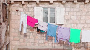 Eski bir binanın penceresinden rüzgarla hareket eden asılı giysileri kapatın. Mimarlık binası sokağı geleneksel seyahat şehri. Yavaş çekim