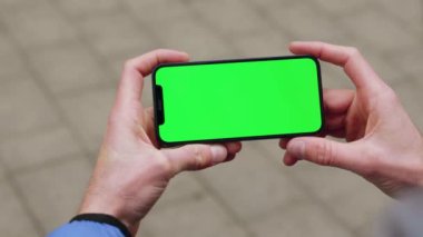 Elinde akıllı bir telefonla arka sokaktaki yatay yeşil ekranlı telefona dokunan bir adam. Mesaj işi adamı aygıtı dijital ekipman interneti. Yavaş çekim