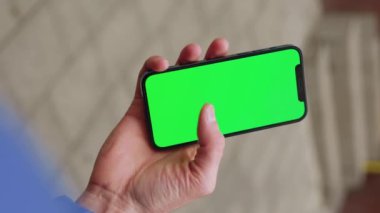 Adam arka sokaktaki yatay yeşil ekranlı telefondan akıllı bir telefon tutarak dikey çekim yapıyor. Mesaj işi adamı aygıtı dijital ekipman interneti. Yavaş çekim