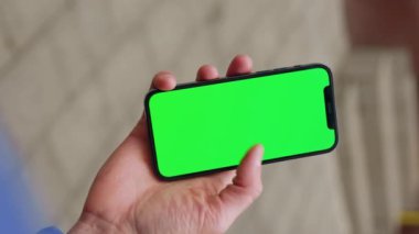 Yavaş çekim adamı arka sokaktaki yatay yeşil ekranlı telefondan akıllı telefon tutarak dikey çekim yapıyor. Mesaj işi adamı aygıtı dijital ekipman interneti. Kapat.