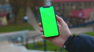 Dikey yeşil ekran arka plan sokak şehri açık havada internet krom bulanıklığı olan bir telefon kullanarak ellerini kapat. Cep telefonu medya aygıtı modern hücresel. Yavaş çekim