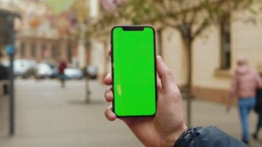 Kapatın elleri adamım. Ağaç şehrinin bulanık internet krom kaplamalı dikey yeşil arka plan sokağı olan bir telefon kullanın. Cep telefonu medya aygıtı. Yavaş çekim