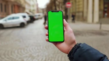 Dikey yeşil ekran arka plan sokak şehrini kullanan eller dışarıda internet krom bulanıklaştırıyor. Cep telefonu medya aygıtı. Yavaş çekim