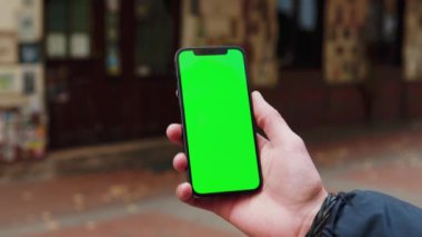 Sokak Terace City 'de yeşil ekran arka planı olan telefon kullanan vurulan adam açık havada internet krom bulanıklığı çekiyor. Cep telefonu medya aygıtı. Yavaş çekim