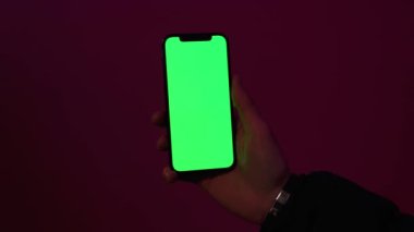 Kapat ellerini adamım, gece lambasında pembe arka planda dikey yeşil ekranlı telefon kullan. İyi akşamlar akıllı telefon ekran uygulaması. Teknoloji dokunmatik hücre ekranı. Yavaş çekim
