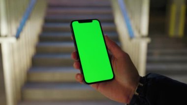 Arka merdivenlerde dikey yeşil ekranlı telefonu tutan ve dokunan bir adama yaklaş. Akıllı telefon dokunmatik dokunmatik dokunmatik interneti göster. Yavaş çekim