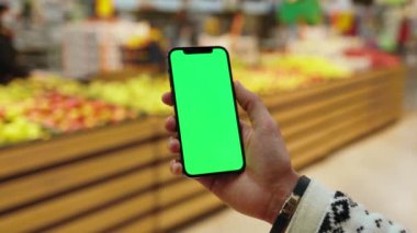 Eller, arka planda bulanık meyveler içeren, dikey yeşil ekranlı cep telefonu kullansın. Limon ve orangutan. Model dinleme görüntülü kromakey telefon. Yavaş çekim