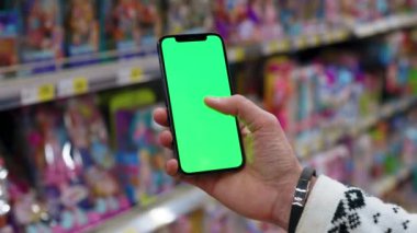 Kapat ellerini adamım dikey yeşil ekranlı arka planda ürünlerle bulanık telefon kullan. Kapalı alanda dokunmatik ekranlı müşteri boş cep telefonu. Alışveriş zamanı. Dükkanda. Yavaş çekim