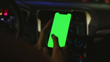 Geceleri adam arabasında dikey yeşil ekran olan telefonu kullanır. Cihaz dijital cihaz, dokunmatik ekranlı mobil telefon teknolojisi. Yavaş çekim
