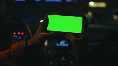 Gece vakti adamın elinde yatay yeşil ekranlı akıllı telefon kullanması. Cihaz dijital cihaz, dokunmatik ekranlı mobil telefon teknolojisi. Yavaş çekim