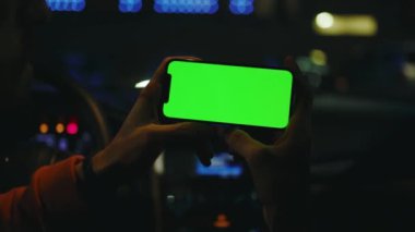 Ağır çekimde çalışan adam gece vakti yatay yeşil ekranlı akıllı telefonu kullanır. Aygıt dijital aygıt telefon dokunmatik ekran trafik mobil teknolojisi.