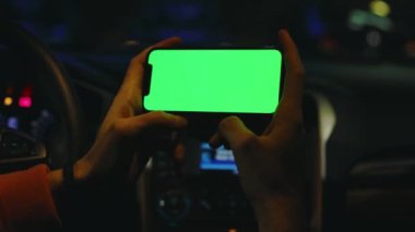 Karanlık ellerde erkekler geceleri arabalarında dikey yeşil ekranlı akıllı telefon kullanırlar. Cihaz dijital cihaz, dokunmatik ekranlı mobil telefon teknolojisi. Yavaş çekim