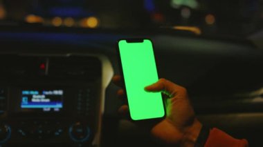 Karanlık ellerde erkekler geceleri arabalarında dikey yeşil ekranlı telefon kullanırlar. Cihaz dijital cihaz, dokunmatik ekranlı mobil telefon teknolojisi. Kapatın. Yavaş çekim