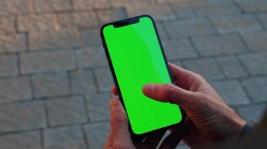 NEW YORK - 19 Aralık 2020: Eller açık arka plan kaldırımında dikey yeşil ekran standı olan telefonu kullanır. Cep telefonu iletişimi dokunmatik ekran dinleme medyası. Yavaş çekim