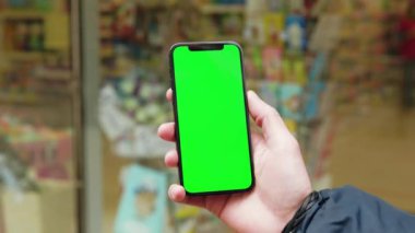 NEW YORK - 19 Aralık 2020: Telefonu dikey yeşil ekran arka plan sokak şehri olan eller açık havada internet krom bulanıklaştırdı. Cep telefonu medya aygıtı. Yavaş çekim